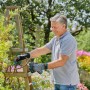 Mann schneidet Rosen mit Gardena Assistcut Gartenschere. Batterieunterstützte Schere für Gartenhandgeräte.