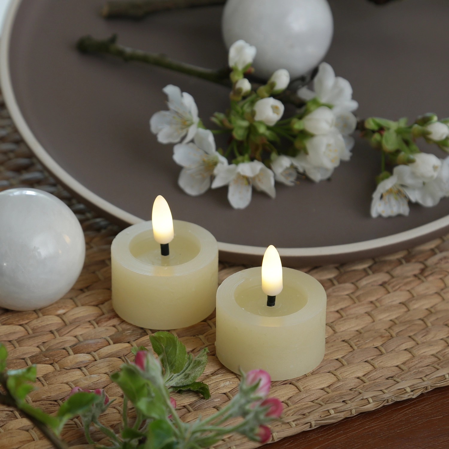 Zwei creme Echtwachs LED Teelichter mit Timer und rustikaler Optik auf Tischdeko.