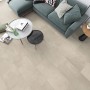 Verlegtes ECO4ALL Pro Bella Grigia Vinyl, Steinoptik, im Wohnraum mit Sofa und Tischen.