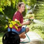 Frau bewässert Garten mit Schlauch. Im Vordergrund: Relaxdays Schlauchtrommel.