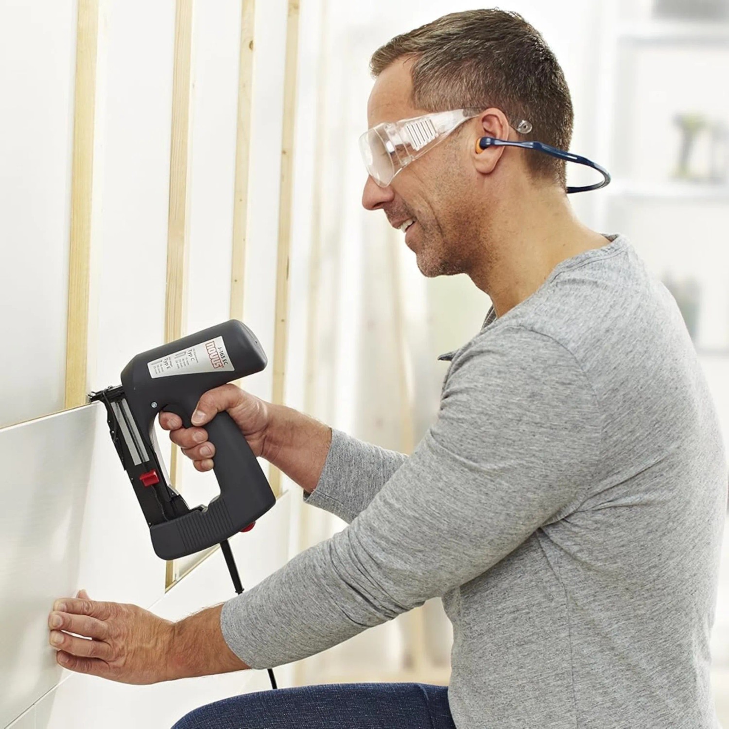 Mann benutzt Novus Elektrotacker J-165 Panel zum Anbringen einer Zierleiste.