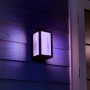 Schwarze Philips Hue Impress LED-Wandleuchte mit farbigem Licht an Hauswand.