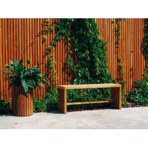 Lackierter Sichtschutzzaun Quadra (90x180cm) mit Bepflanzung und Bank vor Holzwand.