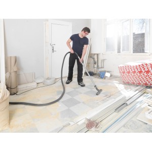 Mann saugt mit Nilfisk Nass- und Trockensauger Attix 30-21 PC eine Baustelle.