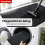Anthrazit melierte Schmutzfangmatte wird gesaugt und in Waschmaschine gelegt. Waschbare, rutschfeste Fußmatte für Eingangsbereich.