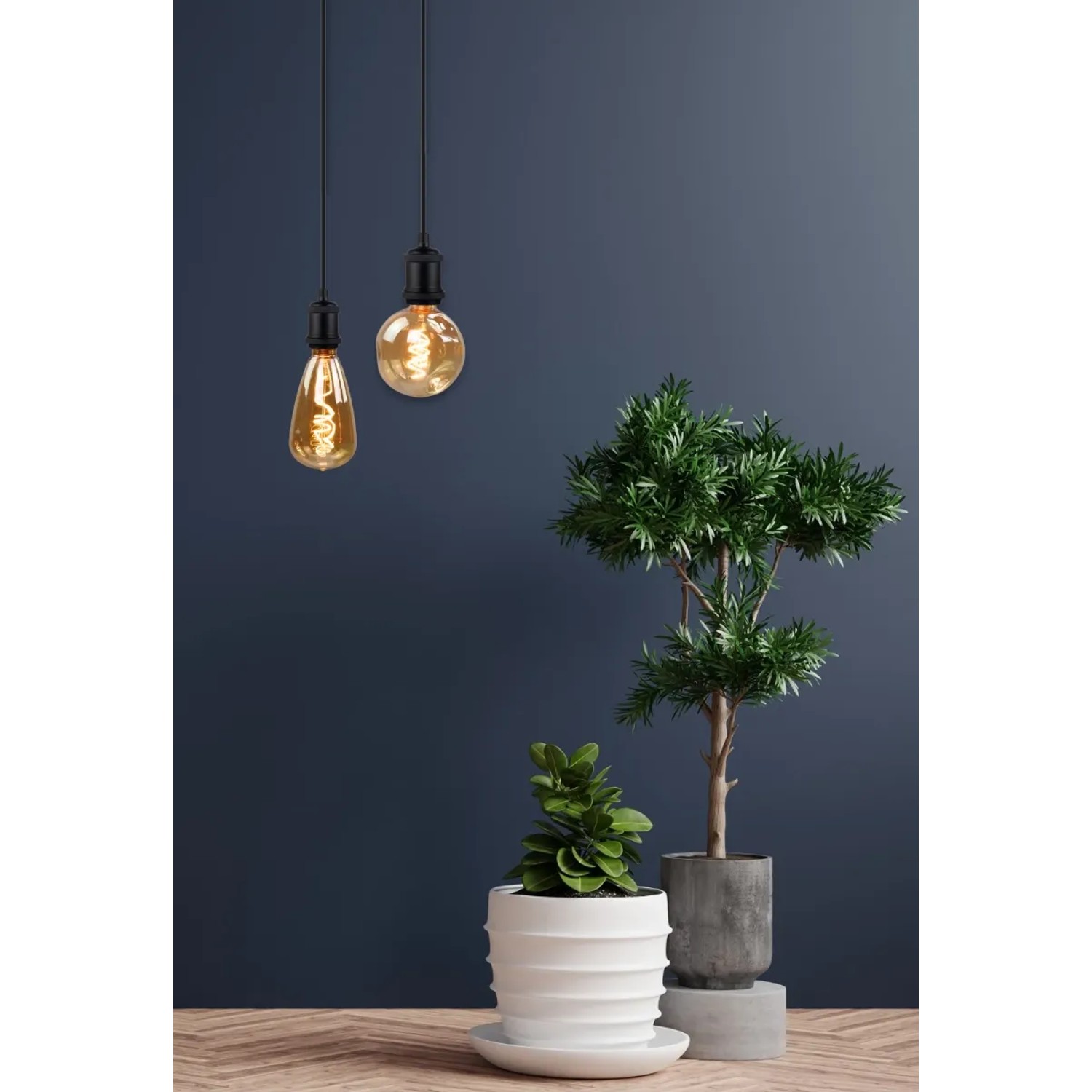Zwei dimmbare LED Filament Leuchtmittel CALDERA E27 4W in Bernstein mit Pflanzen auf Tisch.