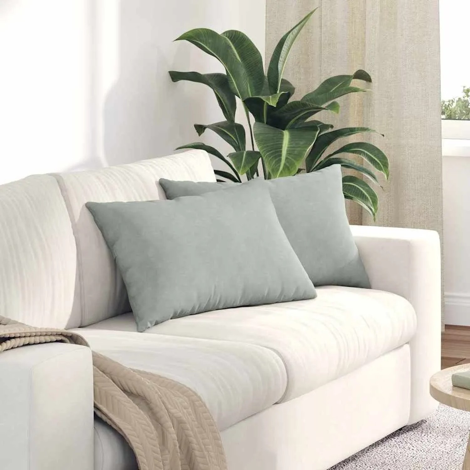 Zwei hellgraue Sofakissen aus Cordstoff auf einem weißen Sofa. Ideal für Wohnzimmer und Komfort.