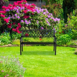Schwarze Gartenbank aus Gusseisen und Stahl für 2 Personen mit dekorativer Flechtmuster-Rückenlehne im grünen Garten.