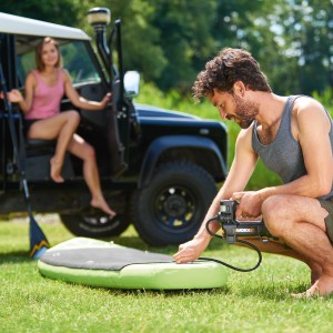 Mann pumpt Stand-Up-Paddleboard mit Worx Akku-Kompressor WX092.9 auf.