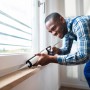 Handwerker dichtet Fenster mit LUX Kartuschenpresse ab.