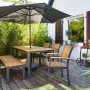 Rechteckiger Gartentisch Bonlee aus FSC®-Holz, braun, 166x90 cm, mit Sitzbank und Sonnenschirm auf Terrasse.