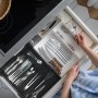 Ausziehbarer Besteckkasten aus Bambus-MDF in Schwarz in Küchenschublade, gefüllt mit Besteck. Hand sortiert Utensilien.