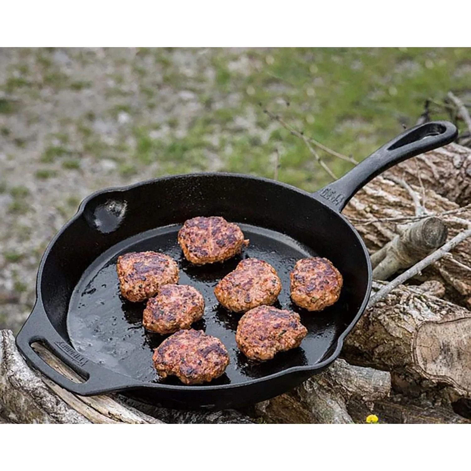 Petromax Feuerpfanne FP30-T: Gusseisenpfanne (Ø 30cm) mit Stiel und Bratlingen auf offenem Feuer.