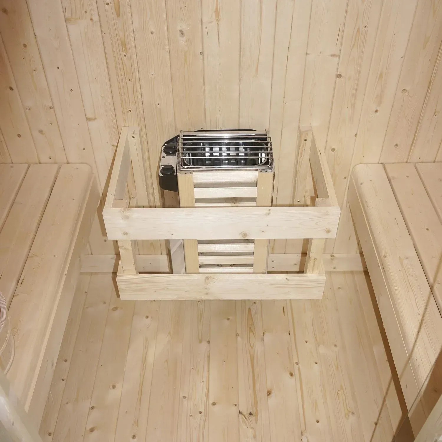 Innenansicht Artsauna Nolvik M Fasssauna: Holzofen und Bänke aus Fichtenholz.