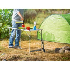 LUX Multifunktionstisch Comfort im Einsatz beim Camping mit Zelt, Geschirr und Lampe.