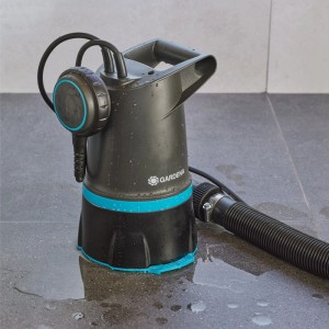 Gardena Hochwasser-Set 20000 Basic mit Pumpe und Schlauch auf nassem Untergrund.