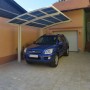 Winterweißer Ximax Carport Portoforte-80 mit blauem Auto darunter. Moderner Metallcarport mit gebogenem Dach.
