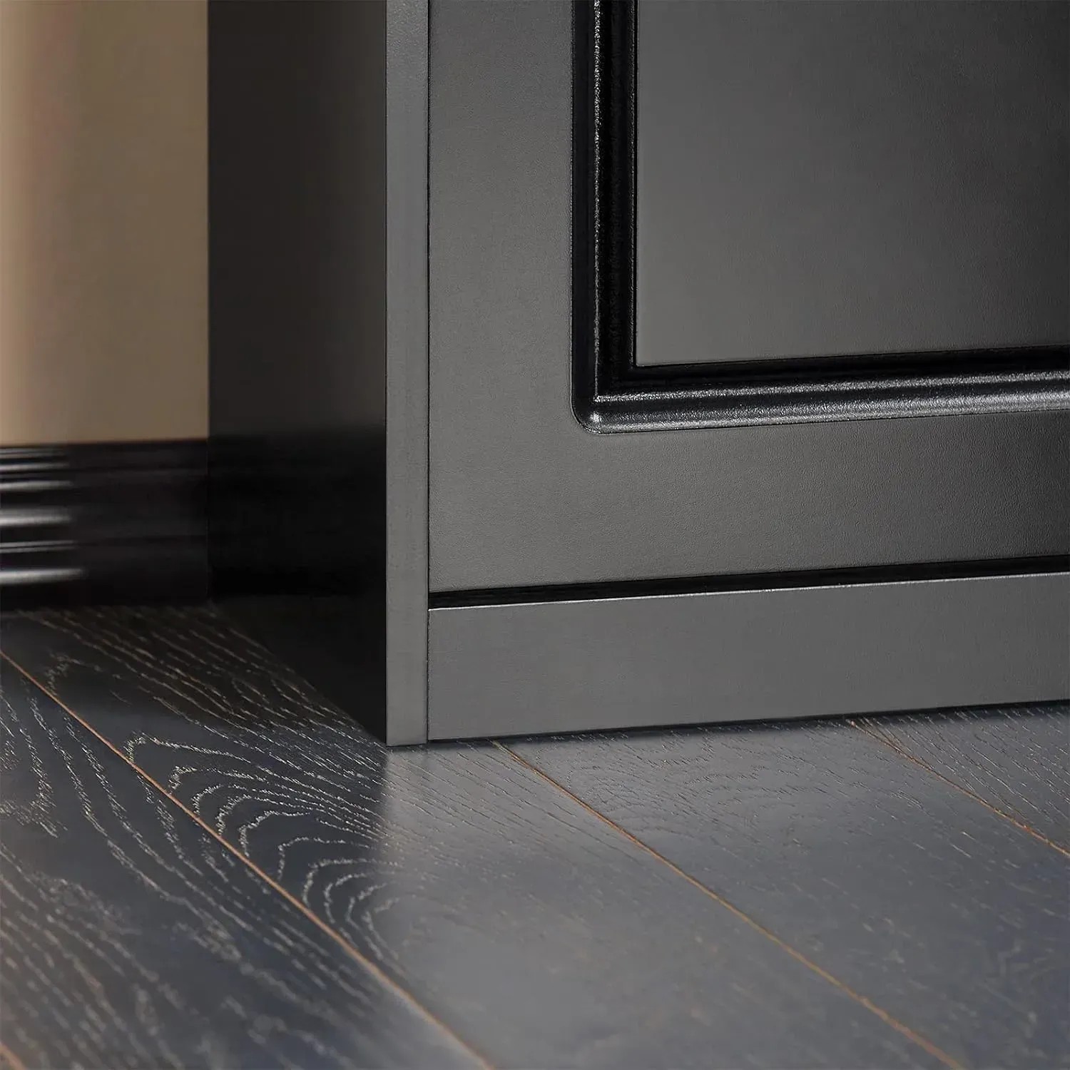 Detailaufnahme: Schwarzer Schuhkipper mit Klappe und Sitzkissen auf dunklem Holzboden.