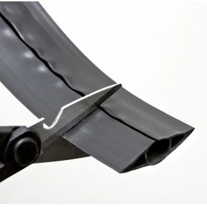 Schwarzer D-Line Fussboden Kabelkanal CC-1 wird mit einer Schere zugeschnitten.