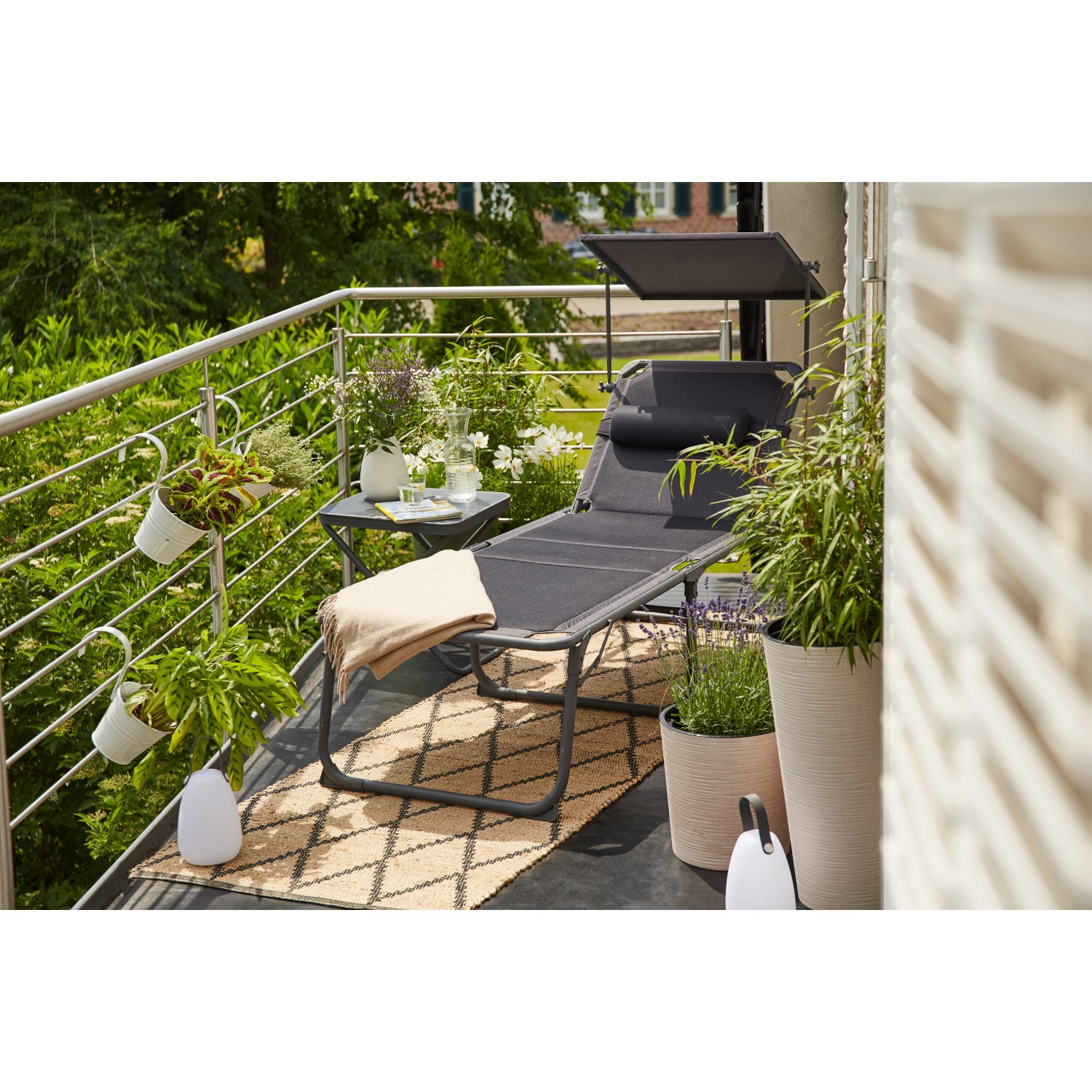 Anthrazitfarbene Siena Garden Campingliege Premium mit Sonnenschutz auf einem Balkon.