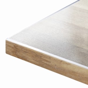 Detailansicht der transparenten, mattierten KARAT Tischfolie Imperial mit abgeschrägter Kante auf einem Holztisch.