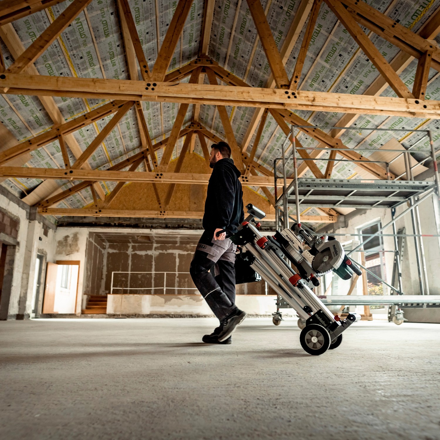 Mann transportiert Metabo Kappsäge KGS 216 M Set auf Rollwagen in Halle.