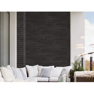 Elabrick Verblender Berlin, 4 cm x 37 cm, in dunkler Steinoptik an einer Wand hinter einer Couch.