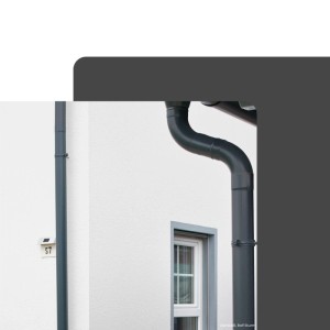 Zambelli Fallrohrbogen 85 Grad DN 80 Kupferbraun verzinkt, an weißer Hauswand installiert. Dachentwässerung.