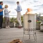 Feuerhand Pyron Feuertonne aus Edelstahl (25 l) mit Feuer und Personen im Hintergrund.