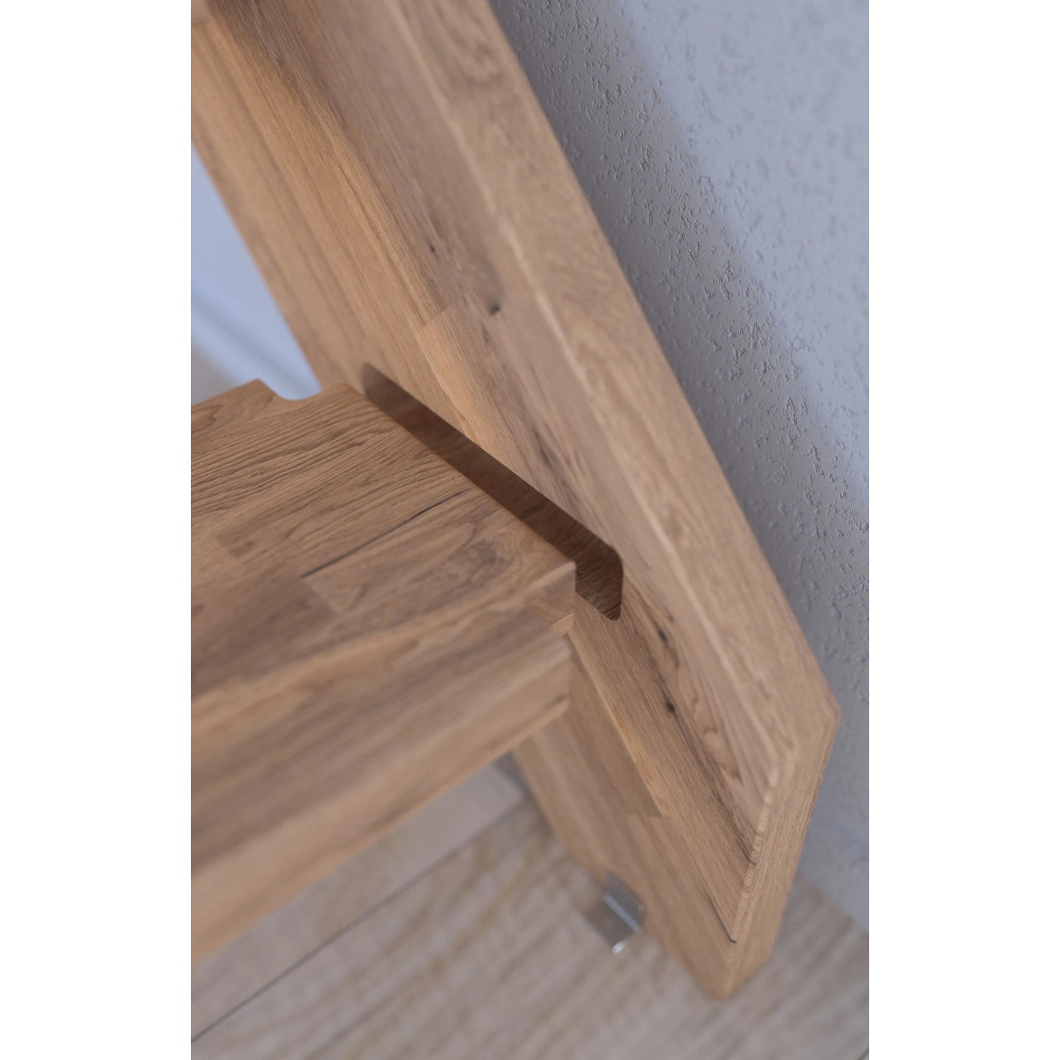 Detailaufnahme einer Mykonos Pro Eichentreppe mit Setzstufe und Holz-Edelstahl-Geländer in Weiß.