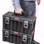 Mann trägt zwei schwarze PROREGAL QBRICK Werkzeugkoffer mit Klemmverschlüssen.