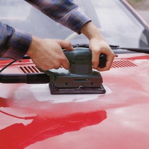 Schwingschleifer mit LUX Schleifvlies Set in Nutzung auf roter Motorhaube.