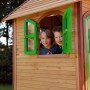 Spielhaus Laura mit Leiter und Rutsche: Kinder schauen aus dem Fenster des Holzspielhauses.