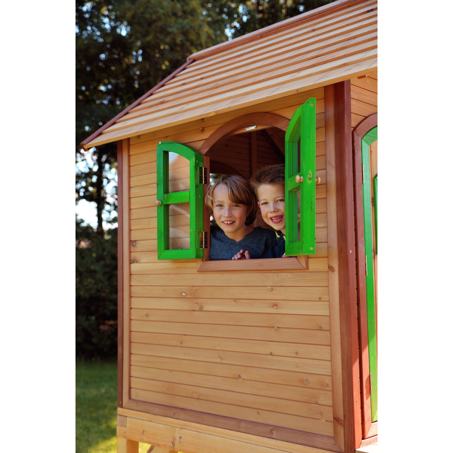 Spielhaus Laura mit Leiter und Rutsche: Kinder schauen aus dem Fenster des Holzspielhauses.