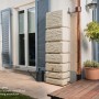 4rain Wandtank Slim Stone Decor 350 l in Sandbeige vor Hauswand. Regentonne mit Steinoptik.