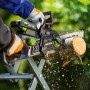 Person sägt mit LUX-TOOLS 20 V Akku-Kettensäge einen Holzstamm auf einem Sägebock. Holzspäne fliegen im Garten.