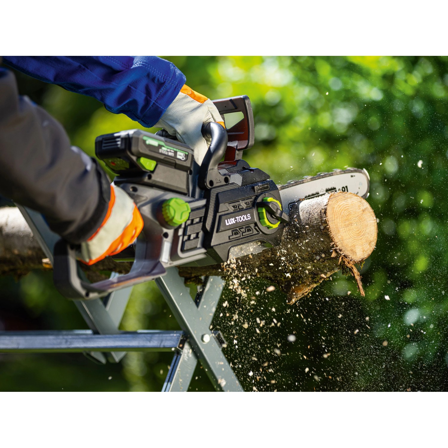 Person sägt mit LUX-TOOLS 20 V Akku-Kettensäge einen Holzstamm auf einem Sägebock. Holzspäne fliegen im Garten.