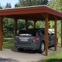 Skan Holz Einzelcarport in Nussbaum mit Auto. Holzcarport mit Flachdach und acht Pfosten.