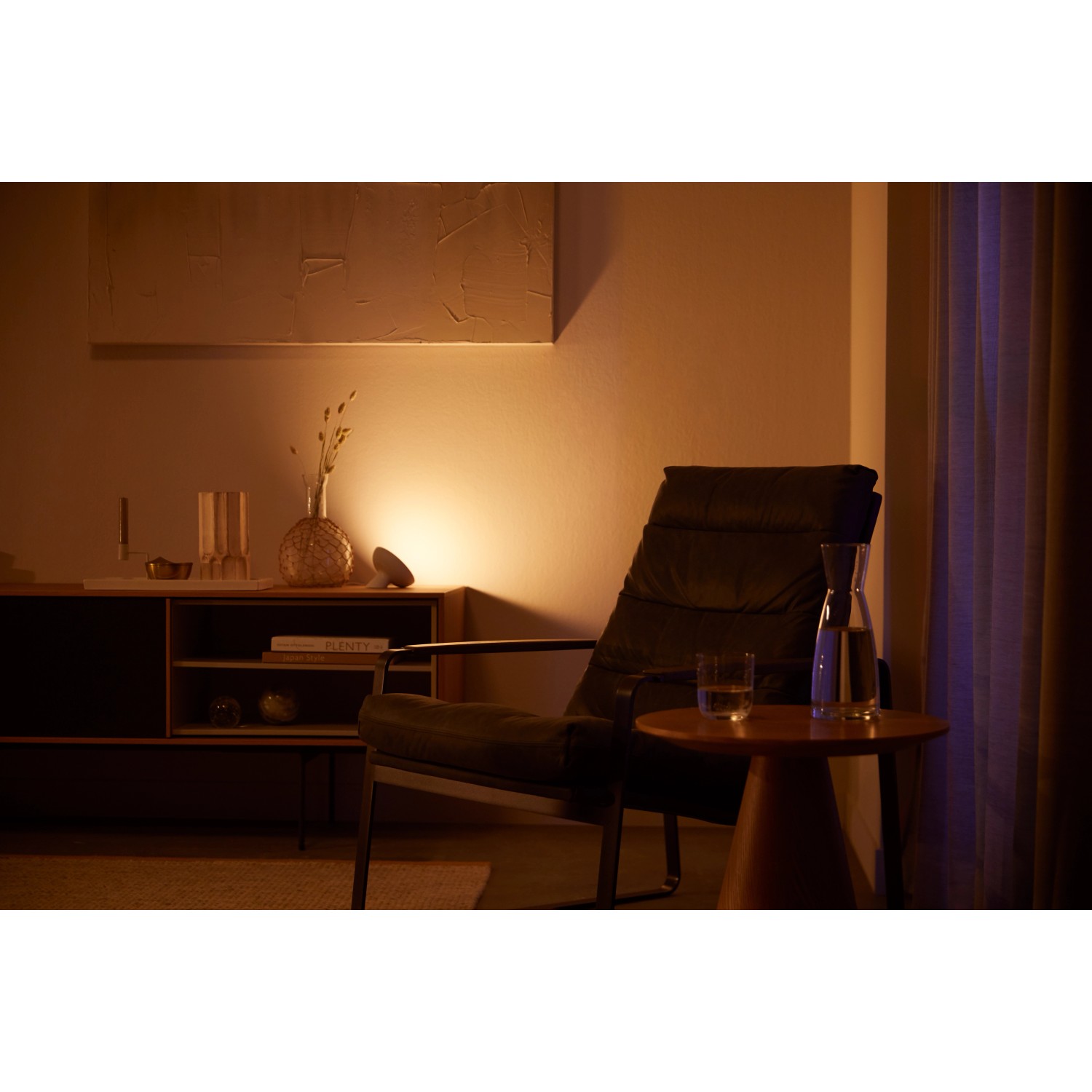 Philips Hue Bloom LED-Tischleuchte in Weiß, warmes Licht im Wohnraum.