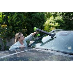 Frau trocknet Windschutzscheibe mit grün-schwarzem Greenworks Akku-Laubbläser. Ideal für kabellose Fahrzeugpflege.