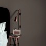 Dunkelgraue Erismann Vliestapete Spotlight InStyle an Schlafzimmerwand mit Nachttischlampe.