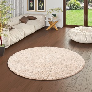Beiger, runder Snapstyle Hochflor-Teppich Milano (100x100 cm) im Wohnzimmer.