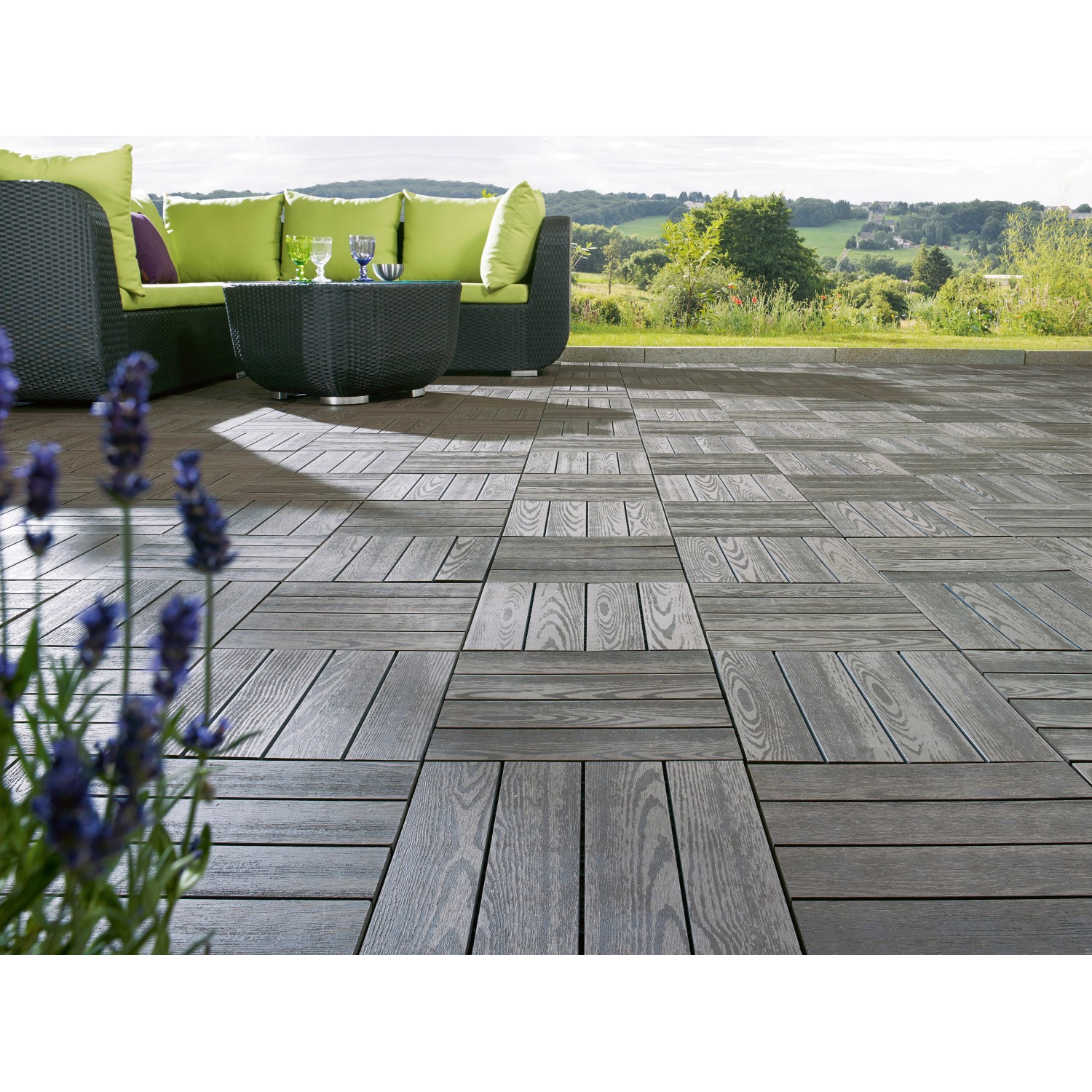 Verlegte, anthrazitfarbene WPC Klickfliesen in Holzoptik auf einer Terrasse mit Gartenmöbeln.