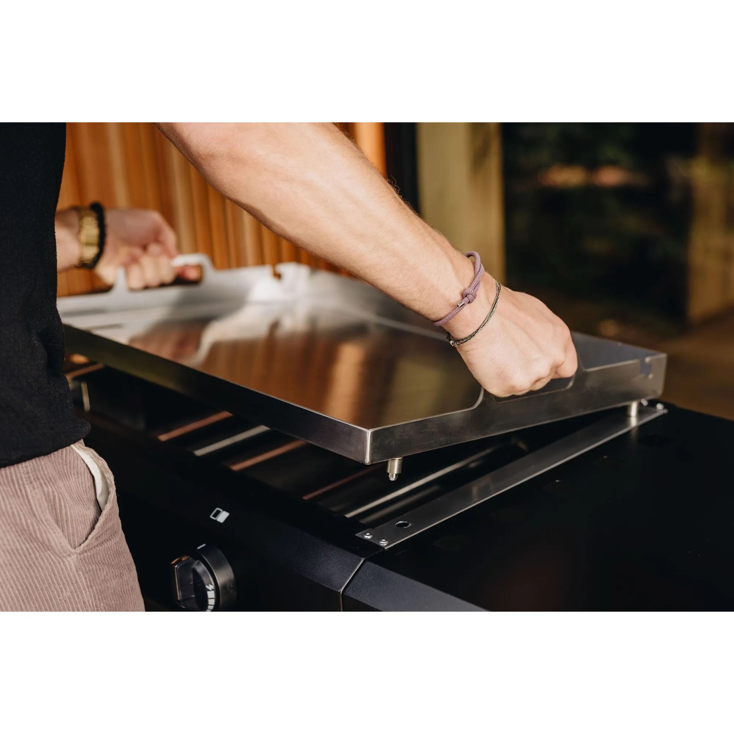 Enders Plancha-Grill Amaro 2: Person setzt Edelstahl-Grillplatte auf Gasgrill.
