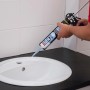 Anwendung von Soudal Fix All Kraftkleber Crystal/Kristallklar aus der Kartusche auf ein Waschbecken.