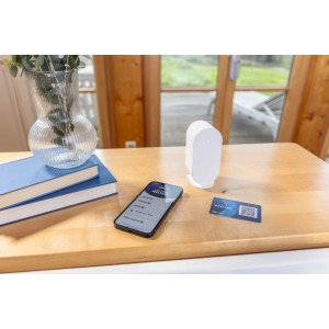 Abus Bridge One CFW4100 in Weiß mit Smartphone und Keycard auf einem Tisch.