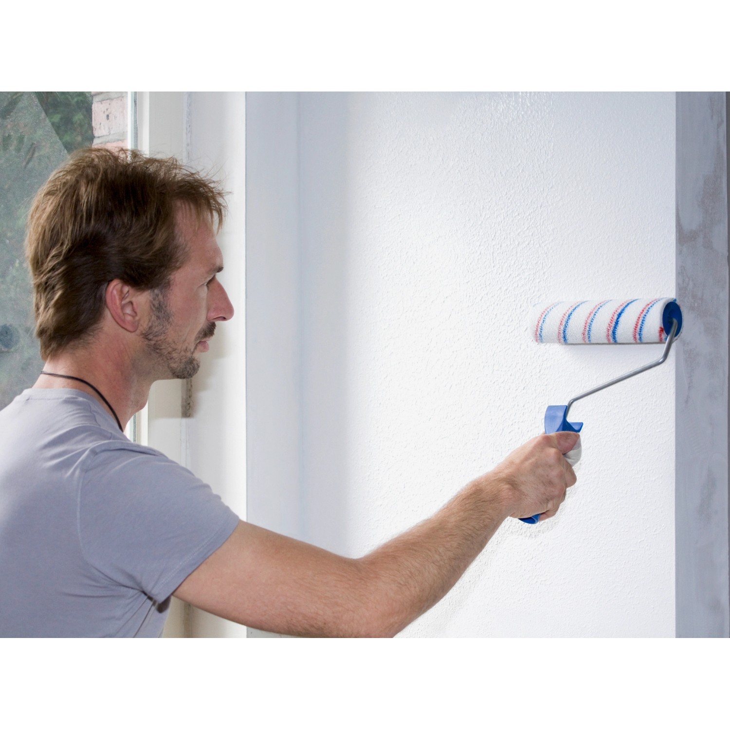 Mann streicht Wand mit Knauf Easy Putz Extra Fein (20kg) und Farbrolle. Putz für Innen.