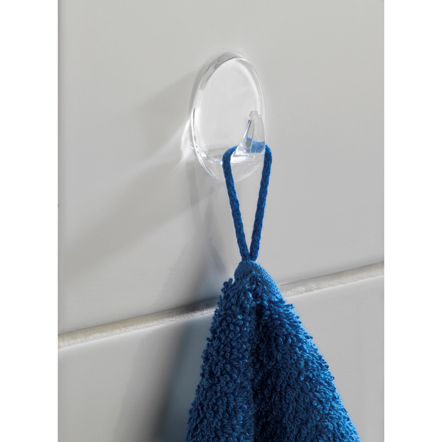 Transparentes Wenko Liliputhaken 3er-Set mit blauem Handtuch an weißer Wand.
