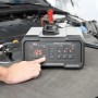 AEG Batterieladegerät CW10 in Anwendung vor einem Auto, digitales Display zeigt 12.5