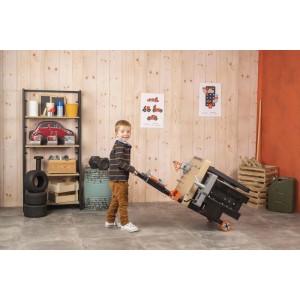 Junge zieht Smoby Black+Decker Mega Werkbank Center mit 3 Spielbereichen.